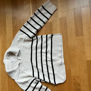 Randig tröja  - Säljer en ljus  tröja från Gina Tricot med svarta horisontella ränder. Tröjan har en krage med liten v-ringning och långa ärmar. Perfekt för dig som gillar klassisk stil med en twist. Säg till om du vill ha fler bilder❣️