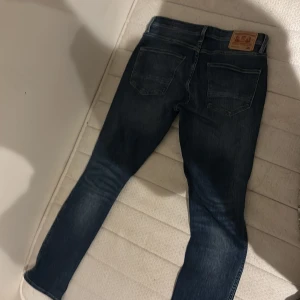 Levi's 521 blå jeans - Säljer ett par klassiska Levi's 521 jeans i blå denim. Byxorna har fem fickor, raka ben och normal passform. Märket syns tydligt på läderpatchen bak. Perfekta för dig som gillar tidlös stil och vill ha ett par jeans som funkar till allt.