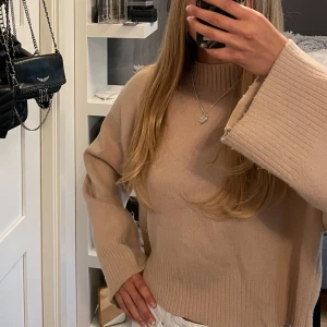 Beige stickad tröja - Beige stickad tröja med breda, långa ärmar och ribbade muddar vid ärmslut, halsringning och nederkant. Står ingen storlek men skulle säga är en S men passar XS och M också! 