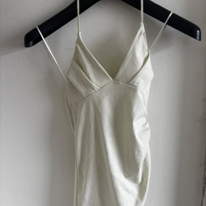 Vit topp - Topp från Zara som är helt oanvänd med prislapp kvar. Sitter smickrande på och har en fin urringning vid bysten samt snedskriven nertill. Passar xs-m. Köpte själv för 149kr men kan sälja för 120kr 