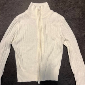 Vit ribbstickad zip-tröja, XS - Krämvit ribbstickad tröja med hög krage och dragkedja framtill. 