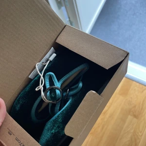 Gröna sammetsballerinaskor från MNG - Snygga ballerina i mörkgrön sammet från MNG med rund tå och justerbart spänne. Skorna har en platt sula och blågröna kantband som ger en extra cool touch. Perfekta för dig som vill sticka ut med en unik och trendig look.