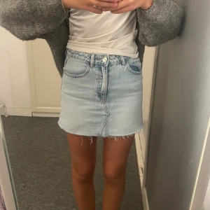 Ljusblå jeanskjol från mango XS - Ljusblå jeanskjol från MNG i klassisk femficksmodell. Kjolen är kort med rå, fransig fåll och har bälteshällor samt knapp och dragkedja framtill. Perfekt för en chill och trendig look.🩵💙