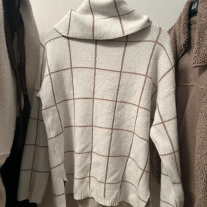 Vit polotröja med brunt rutmönster - Säljer en vit polotröja från shein med brunt rutmönster. Tröjan har en bred polokrage och är långärmad med avslappnad passform. Materialet är mjukt och stickat