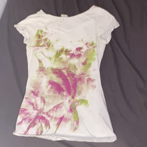 Vit t-shirt med palmtryck från Esprit - Vit t-shirt från Esprit med färgstarkt tryck i rosa och grönt som föreställer palmer och surfmotiv. Modellen är figurnära med korta ärmar och rund halsringning. Perfekt för dig som gillar en chill och somrig vibe. Jag älskar den men den kommer typ aldrig till användning.🩷