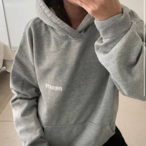 Grå hoodie från PRIVATE i medium - Säljer en grå hoodie från PRIVATE i storlek medium. Hoodien har en stor huva, magficka och tryck med texten PRIVATE både fram och bak. Den är i mjuk bomullsblandning och har en relaxed, lite oversized passform. Perfekt för chill dagar eller när du vill vara extra bekväm.