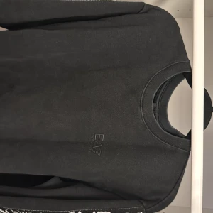 Svart EA7 Emporio Armani sweatshirt - Svart sweatshirt från EA7 Emporio Armani med broderad logga på bröstet och stora vita logotexter längs ena ärmen. Klassisk rund halsringning och långa ärmar. Perfekt för dig som gillar stilrena och trendiga märkesplagg.