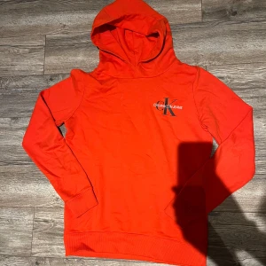 Calvin Klein Tröja  - Snygg orange hoodie från Calvin Klein. Inte alls så använd, inga biverkningar som skulle märkas, så i bra skick. Pris kan diskuteras. S, skulle fungera för M men blir lite mer trång. 