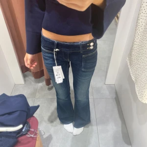 Jeans - Snygga mörkblå jeans med låg midja och bootcut-ben. Jeansen har två knappar i midjan och klassiska fickor fram. 