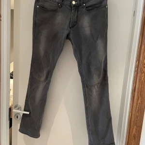 Grå jeans från Acne Jeans, straight fit - Säljer ett par gråa jeans från Acne Jeans i rak modell. Jeansen har klassisk femficksdesign, silverfärgade nitar och knapp, samt diskret tvättad look. Materialet är bomull med lite stretch för extra komfort. Perfekta för en clean och avslappnad stil. 33/32 men funkar för 32/32