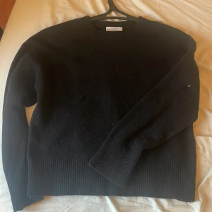 Svart stickad tröja från Other Stories - Mysig svart stickad tröja från Other Stories. Klassisk rund halsringning och ribbade muddar vid ärmslut och nederkant. Perfekt för lager-på-lager och enkel att matcha med jeans eller kjol. Använd sparsamt så skicket är toppen.