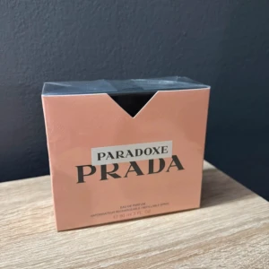 Prada Paradoxe Eau de Parfum 90ml - Prada Paradoxe Eau de Parfum i en snygg, persikofärgad kartong med svart och silverdetaljer. Flaskan rymmer 90 ml och är påfyllningsbar. Lyxig och modern doft från ett av världens mest ikoniska modehus.