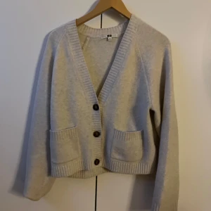 Beige kofta från Uniqlo med knappar - Mysig vit kofta från Uniqlo. Väldigt använd där av priset, kostar egentligen 500kr 