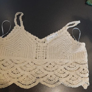 Beige virkad topp från Vila storlek xs  - Säljer en söt beige virkad topp från Vila. Den har smala axelband och ett vackert mönster med vågformade detaljer. Perfekt för varma dagar eller som ett lager under en jacka.