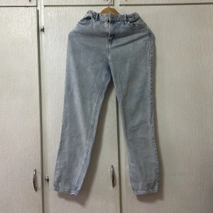 Grå jeansbyxor från Lindex - Snygga grå jeansbyxor från Lindex med en klassisk design. Byxorna har en normal passform och är perfekta för en avslappnad stil. De har en traditionell femficksdesign och är tillverkade i ett bekvämt denimtyg.