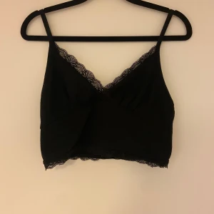 Svart spetskantad linne - Snygg svart v-ringad linnetopp med spetsdetaljer längs kanterna. 