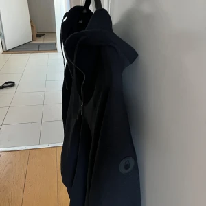 Svart jacka från Sail racing - Snygg svart jacka från sail racing med dragkedja och huva. Perfekt för en stilren look. Jackan/hoodien har en enkel design med diskreta detaljer och är tillverkad i ett bekvämt material.✅.    Storlek M✅ Mitt pris är 500kr 👏✅