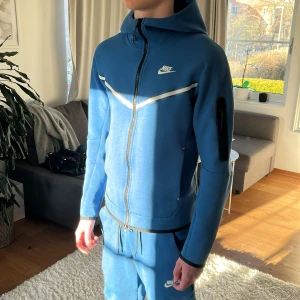 Nike Tech Fleece Blå - Tja! Säljer nu min Nike Tech i färgen blå då jag inte använder den längre. Den är storlek XS och du får byxor och hoodie på köpet! Skön och färgen blå passar bra nu till våren. Två små slitningar där bak på byxorna men som knappt syns under användning. Om du har några frågor är det bara ställa dem! Mvh 