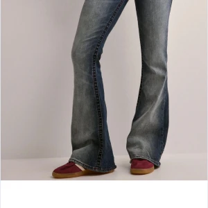 Blå bootcut jeans från True Religion - BYTE ELLER TILL SALU! vill gärna byta dom här mot ett par likadana i W27, storleken är helt slut men vill gärna byta för vill ha kvar byxorna! Som har prislappar och allt kvar! Snygga blå bootcut jeans från True Religion med klassisk femficksdesign och broderade bakfickor. Jeansen har en lätt tvättad look och är perfekta för en avslappnad stil. De har en lågmidjad passform som ger en retro känsla. 