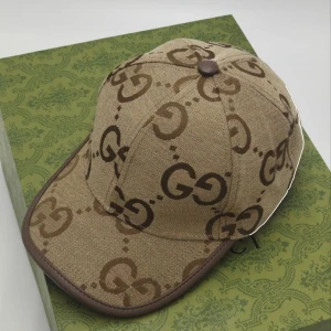 Gucci keps beach  - Snygg beige keps med brunt GG-mönster. Perfekt för att ge din outfit en lyxig touch. Kepsen har en klassisk design med böjd skärm och justerbar passform.