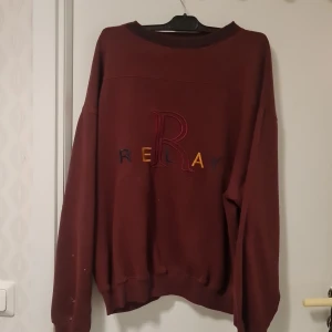 Vinröd tröja från Relay - Säljer en vinröd tröja från Relay med broderad text på framsidan. Tröjan har långa ärmar och en rund halsringning. Perfekt för en avslappnad stil.