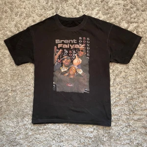 Brent faiyaz Svart t-shirt - Cool svart t-shirt med tryck av en artist och texten 'Brent Faiyaz'. T-shirten har korta ärmar och en normal passform. Perfekt för fans av artisten eller för en avslappnad stil.