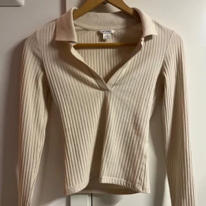 Beige ribbad tröja från Monki - Beige långärmad tröja med v ringning från Monki. Använd fåtal gångger. Storlek xs men tight på mig som brukar ha xs✨