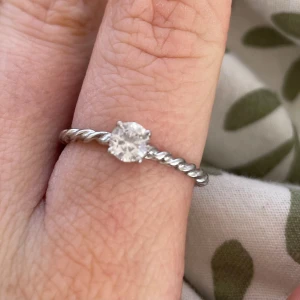 Silverring med tvinnad design och klar sten - Elegant silverring med en tvinnad design och en klar, gnistrande sten i mitten. Perfekt för att lägga till en touch av elegans till din stil.