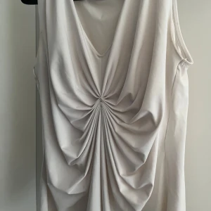 Vit ärmlös topp - Elegant vit topp med draperad detalj framtill. S/M