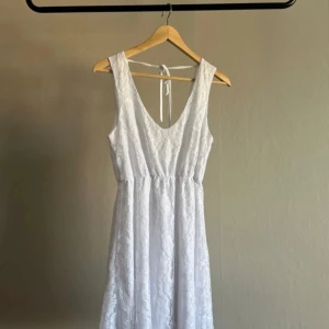 Vit spetsklänning från NLY Blush STUDENTKLÄNNING - Säljer en vacker vit spetsklänning från NLY Blush. Klänningen har en v-ringad design och knytband i ryggen. Perfekt för sommarens alla tillfällen. 💫 snöret på baksidan har en lös tråd, se bild. Annars fin
