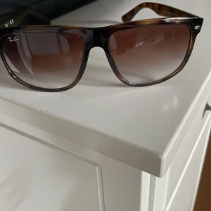 Bruna Rayban boyfriend solglasögon  - Snygga solglasögon från Ray-Ban med en klassisk brun sköldpaddsmönstrad båge. De har en stilren design med mörka tonade glas och den ikoniska loggan på sidan. Perfekta nu till sommaren!