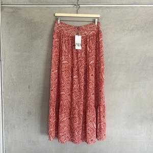 Röd mönstrad långkjol från Zara - Säljer en röd långkjol från Zara, köpptes för ungefär två år sedan och är slutsåld, använd max 5 gånger och är i fint skick🤗