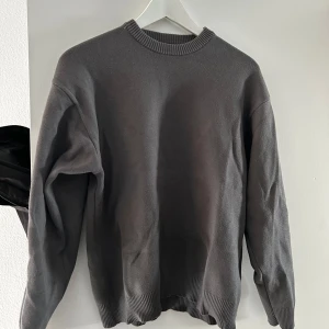 Grå tröja från Zara - Säljer en stilren grå tröja från Zara. Tröjan har en klassisk rund halsringning och långa ärmar. Perfekt för en minimalistisk look. Endast använd en gång.