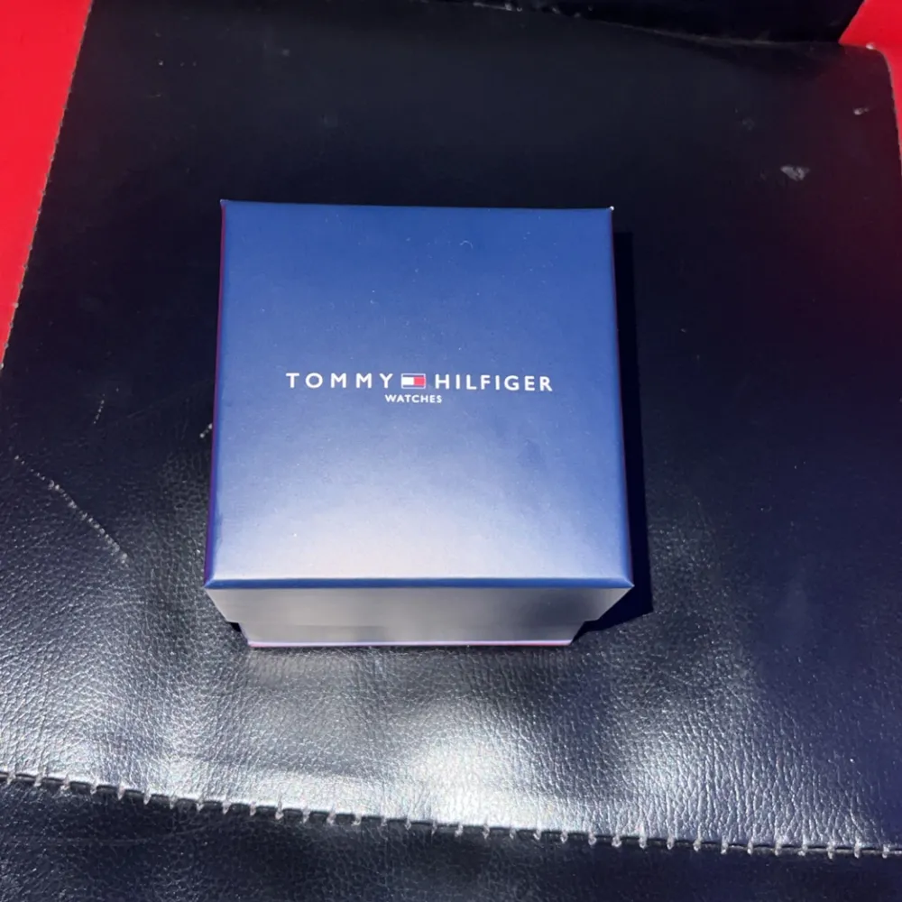 Snygg klocka från Tommy Hilfiger med en stilren design. Klockan har en svart urtavla med tydliga vita siffror och en datumvisare. Armbandet är i silverfärgat metall och kommer i originalförpackning med extra länkar.. Asusteet.