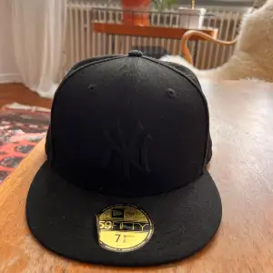 Snygg svart keps från New Era med broderad new york yankees logga framtill. Kepsen är köpt för ett år sedan och är knappt använd då den inte passar mitt huvud.