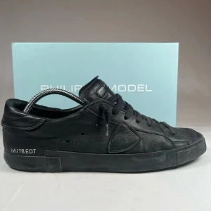 Svarta sneakers från Philippe Model - Snygga svarta sneakers från Philippe Model i skinn. De har en stilren design med snörning och rund tå. Perfekta för en casual look med en touch av elegans.