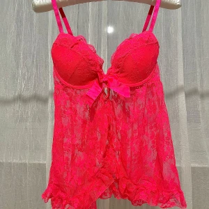 Negligé från H&M - Säljer ett snyggt negligé från H&M med justerbara axelband och en söt rosett framtill. Linnet har en transparent design med volangdetaljer vid nederkanten. Färgen kan beskrivas som neonröd-rosa. STORLEK EU38 eller B75 som passar byst 90-92cm.