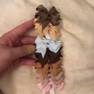 Små rosetter i olika färger på klämma - Säljer ett set med små rosetter i olika färger som beige, brun, ljusblå och rosa. Rosetterna sitter på metallklämmor och är perfekta för att sätta i håret på sidorna. Dom kom i flera färger har tagit dom färgerna jag vill ha kvar men domhär är resten av färgerna, inte använda