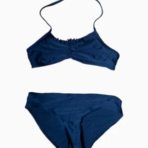 Svart bikini från Lindex - Säljer en svart bikini från Lindex med enkel design. Överdelen har smala axelband och en liten, jättefin volangdetalj framtill. Underdelen är klassisk med normal passform. Trosorna är väldigt sköna och täcker rumpan vilket är skönt och speciellt för yngre. Perfekt för stranden eller poolen! En svart bikini passar verkligen till allt. Säljer både överdelen och underdelen för 120kr 