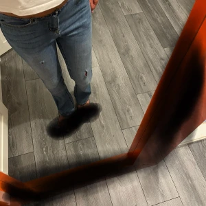 Ljusblå bootcut jeans med slitningar - Säljer ett par ljusblå jeans med bootcut passform och snygga slitningar på benen. Jeansen har klassisk femficksdesign, normal midja och är tillverkade i mjukt denimtyg. Perfekta för en avslappnad och trendig look.