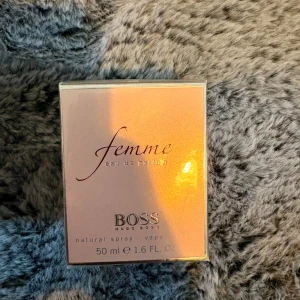 Hugo Boss Femme Eau de Parfum 50ml - Elegant parfym från Hugo Boss, Femme Eau de Parfum, 50 ml. Kommer i en stilren, ljusrosa kartong med silvriga detaljer. Doften är feminin och modern, perfekt för dig som gillar en fräsch och mjuk signatur.
