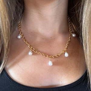Pärlhalsband Guld  - Snyggt halsband med chunky guldfärgad kedja och fem droppformade vita pärlor som hänger längs kedjan. Perfekt statement-piece med trendig vibe och elegant touch. Passar till allt från basic till mer dressade looks.