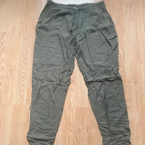 Olivgröna pull-on byxa med snörning - Snygga olivgröna byxor med elastisk midja och snörning framtill. Byxorna har smal passform, resår vid benslut och är perfekta för en avslappnad stil. Lätta och luftiga, passar grymt till sneakers eller sandaler