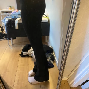 Svarta bootcut kostymbyxor  - Säljer ett par svarta bootcut kostymbyxor med snygg passform. De har en klassisk look med utsvängda ben och sitter tajt upptill. Perfekta att styla med sneakers eller boots. Materialet känns mjukt och stretchigt för extra komfort.