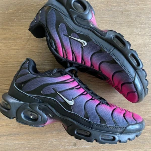 Nike Air Max rosa/svarta sneakers - Nike Air Max sneakers i en grym färgskiftning från rosa till svart med svarta vågformade detaljer och silvrig swoosh. Skorna har en chunky sula med synliga luftbubblor och svart mesh- och syntetöverdel. Perfekta för dig som vill sticka ut med en unik look.