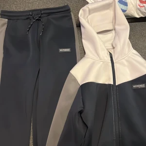 Svarta mjukisbyxor från McKenzie XL - Säljer ett par svarta mjukisbyxor från McKenzie i storlek M för tonåringar. Byxorna har grå sidopaneler, snörning i midjan och en stilren logga på benet. Perfekta för chill eller träning, tillverkade i mjukt syntetmaterial.
