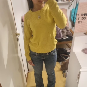 Gul stickad tröja med rund hals - Gul stickad tröja med rund halsringning och ribbade muddar vid ärmslut och nederkant. Tröjan har en klassisk passform och är perfekt för dig som vill ha en färgklick i garderoben. Långärmad och mjuk, passar till jeans eller kjol.