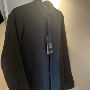 Mörkgrön skjorta/overshirt, aldrig använd - Stilren mörkgrön skjorta/overshirt från Shine Original i storlek S men passar M. Skjortan/overshirten har knäppning framtill och är långärmad. Perfekt för dig som gillar en clean och enkel look. Materialet känns mjukt och passar bra till lager-på-lager. Skick: 10/10, aldrig använd med lappen kvar. Pris: 449kr, nypris: 799kr. Om ni har frågar är det bara att ställa🤗