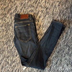 Mörkblå slim jeans från T/J, 31/32 - Snygga mörkblå jeans från Tiger of Sweden i slim fit-modell. Klassisk femficksdesign med kontrastsömmar och läderpatch bak i midjan. Tillverkade i Italien och passar dig som gillar en smalare siluett. Perfekta till sneakers eller boots.