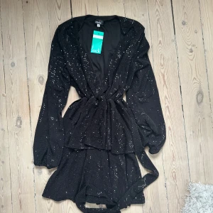 Svart glittrig kortklänning från Zack - Supersnygg svart kortklänning. Helt oanvänd och snygg till mer upppiffat tillfälle. Storlek 38 men passar mig som är S. Då man kan schystera med bandet.